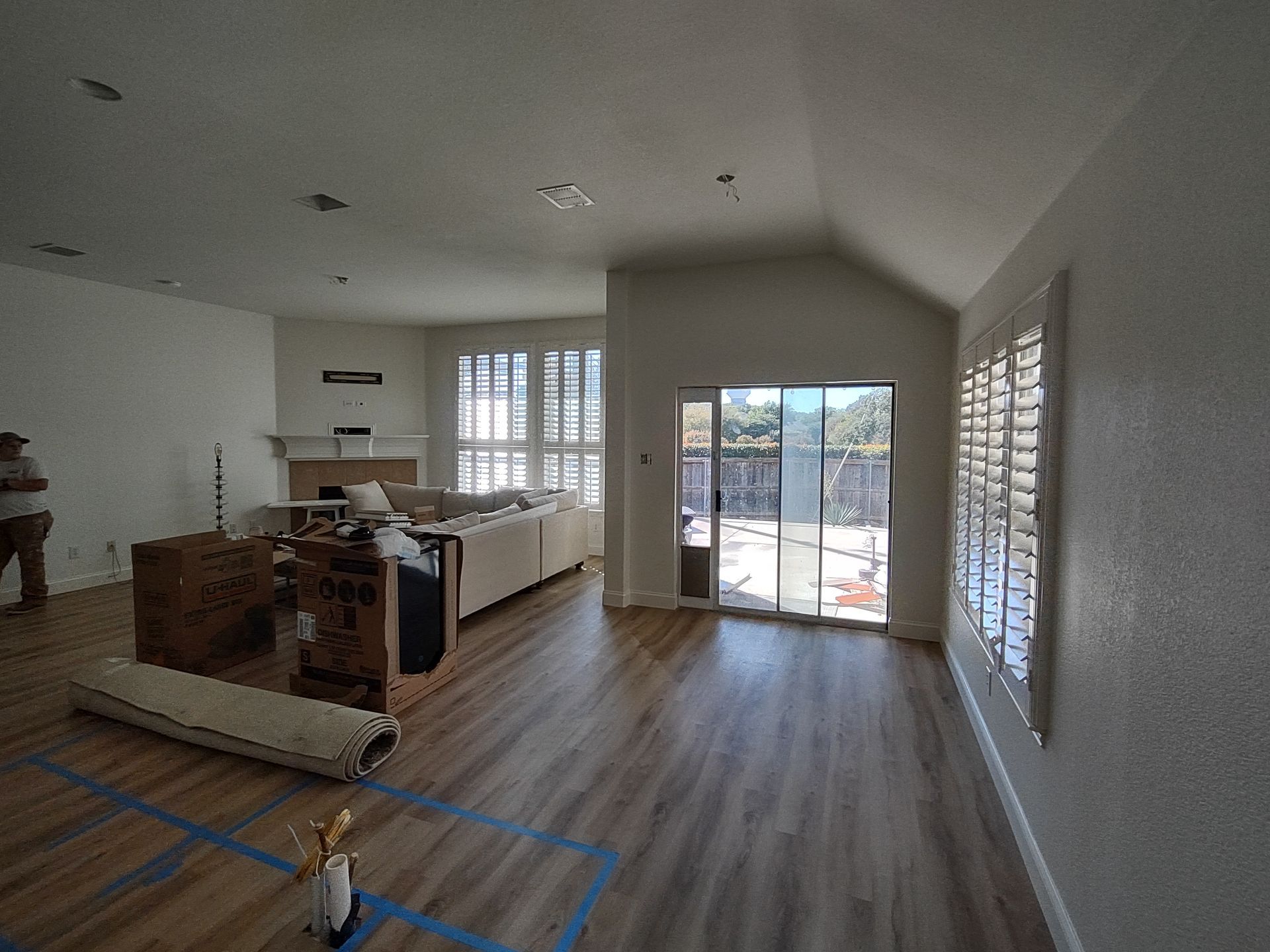 A living room with hardwood floors , a couch , a fireplace and a sliding glass door.