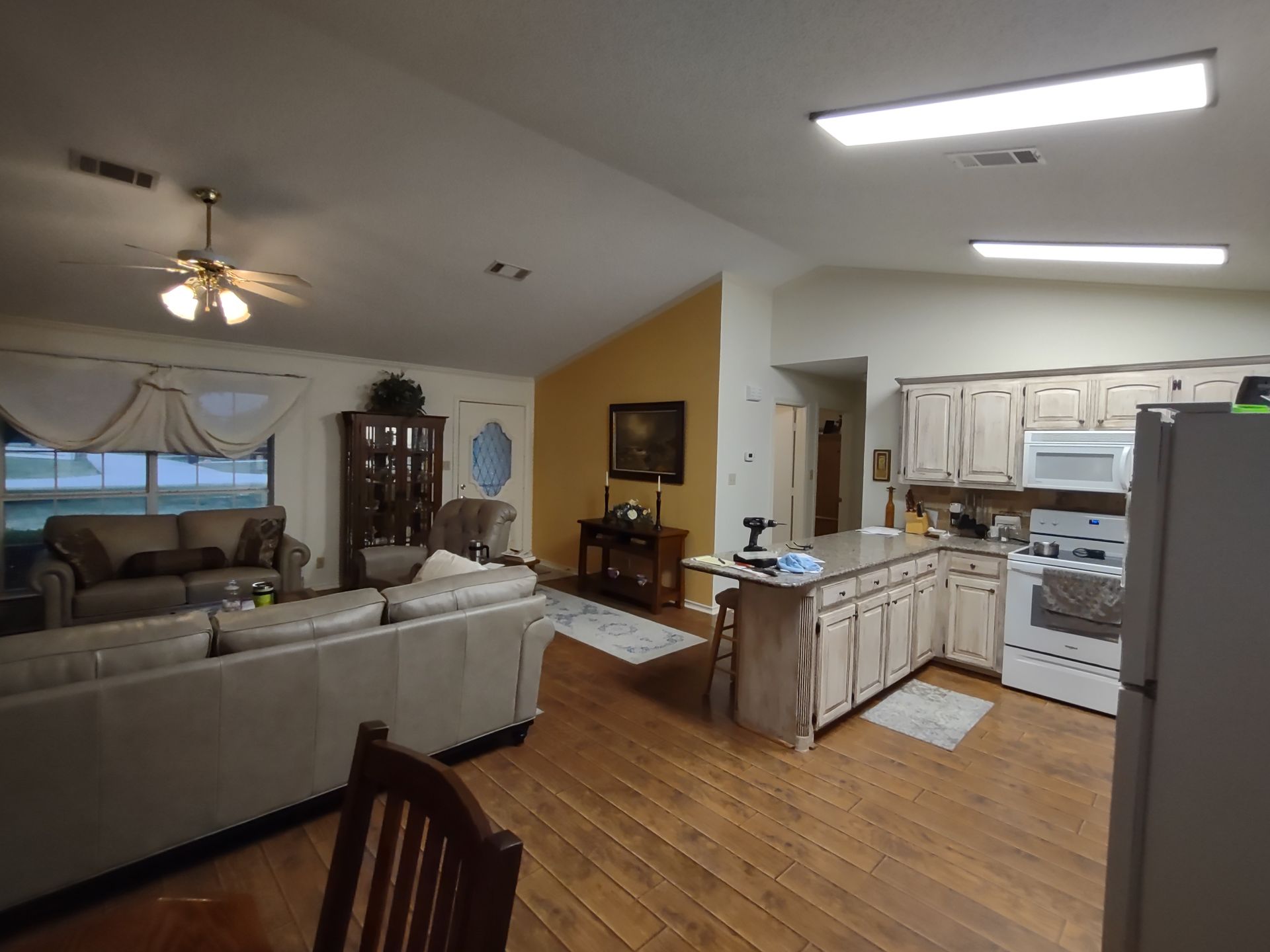 A living room and kitchen in a house with hardwood floors.