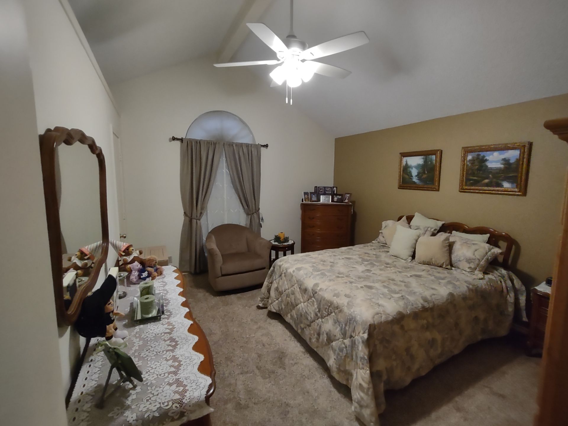 A bedroom with a large bed and a ceiling fan
