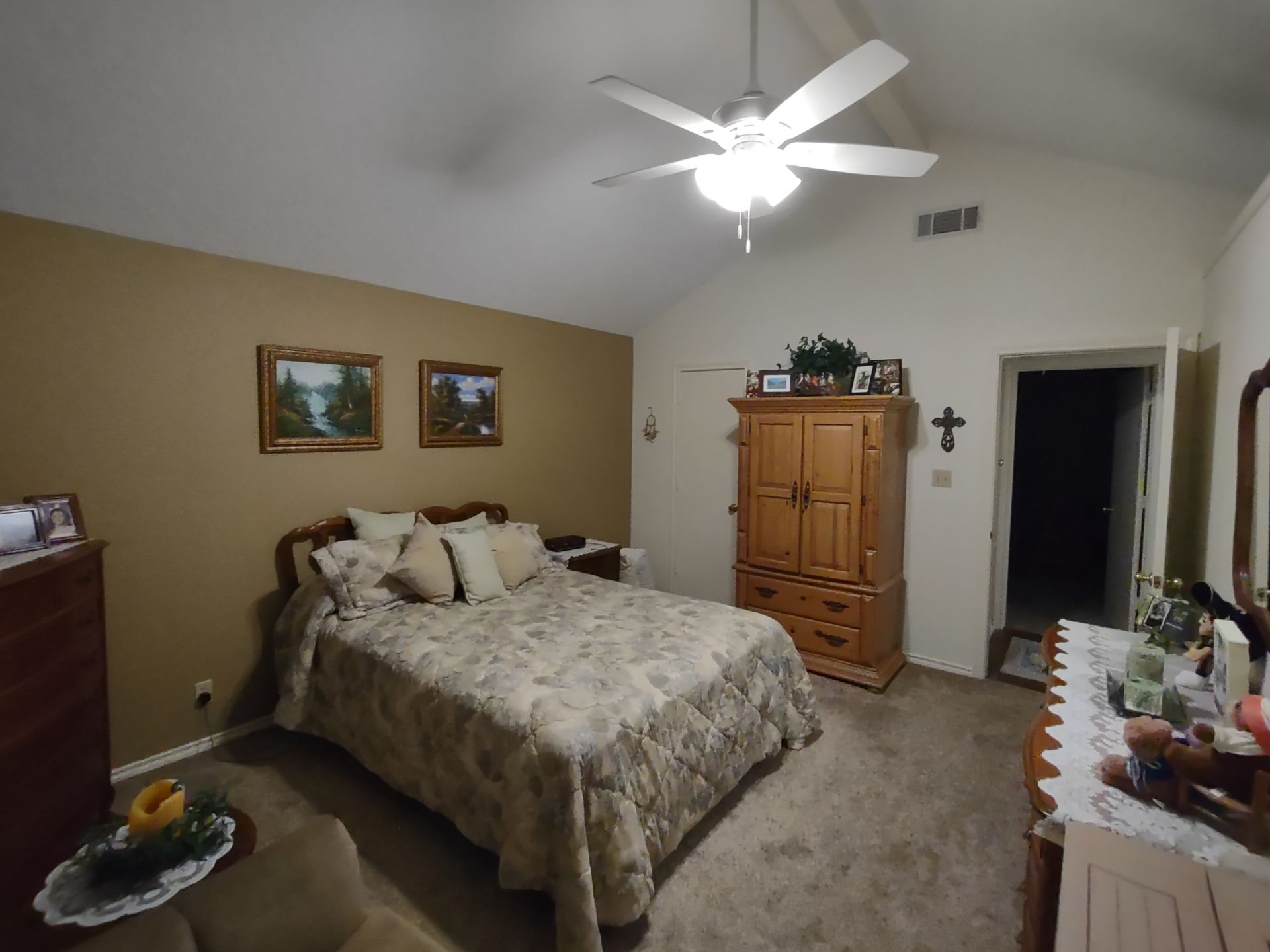 A bedroom with a large bed and a ceiling fan