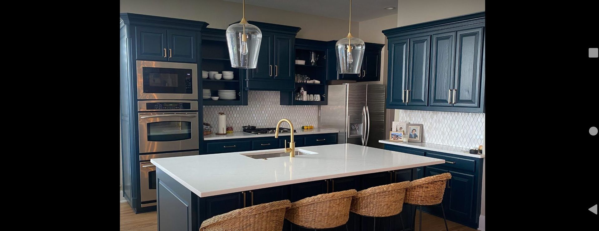 A kitchen with blue cabinets , white counter tops , and a large island.