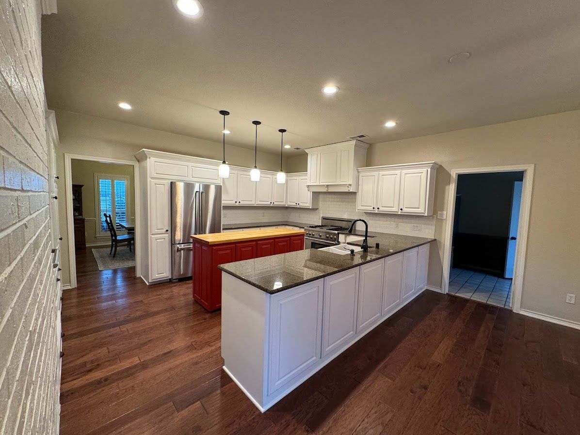 A kitchen with white cabinets , granite counter tops , stainless steel appliances and a large island.