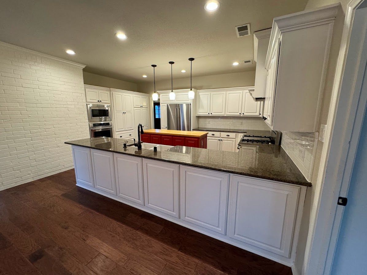 A kitchen with white cabinets , granite counter tops , and stainless steel appliances.