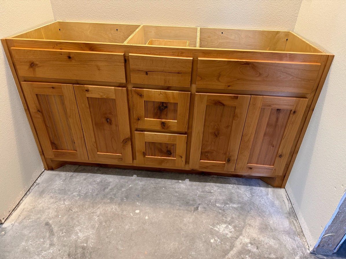 A wooden vanity is sitting on a concrete floor in a room.