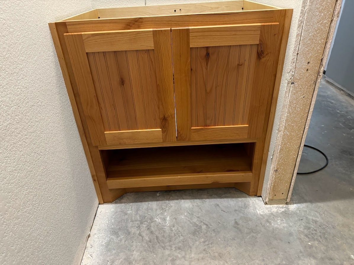 A small wooden cabinet with two doors and a shelf underneath it.