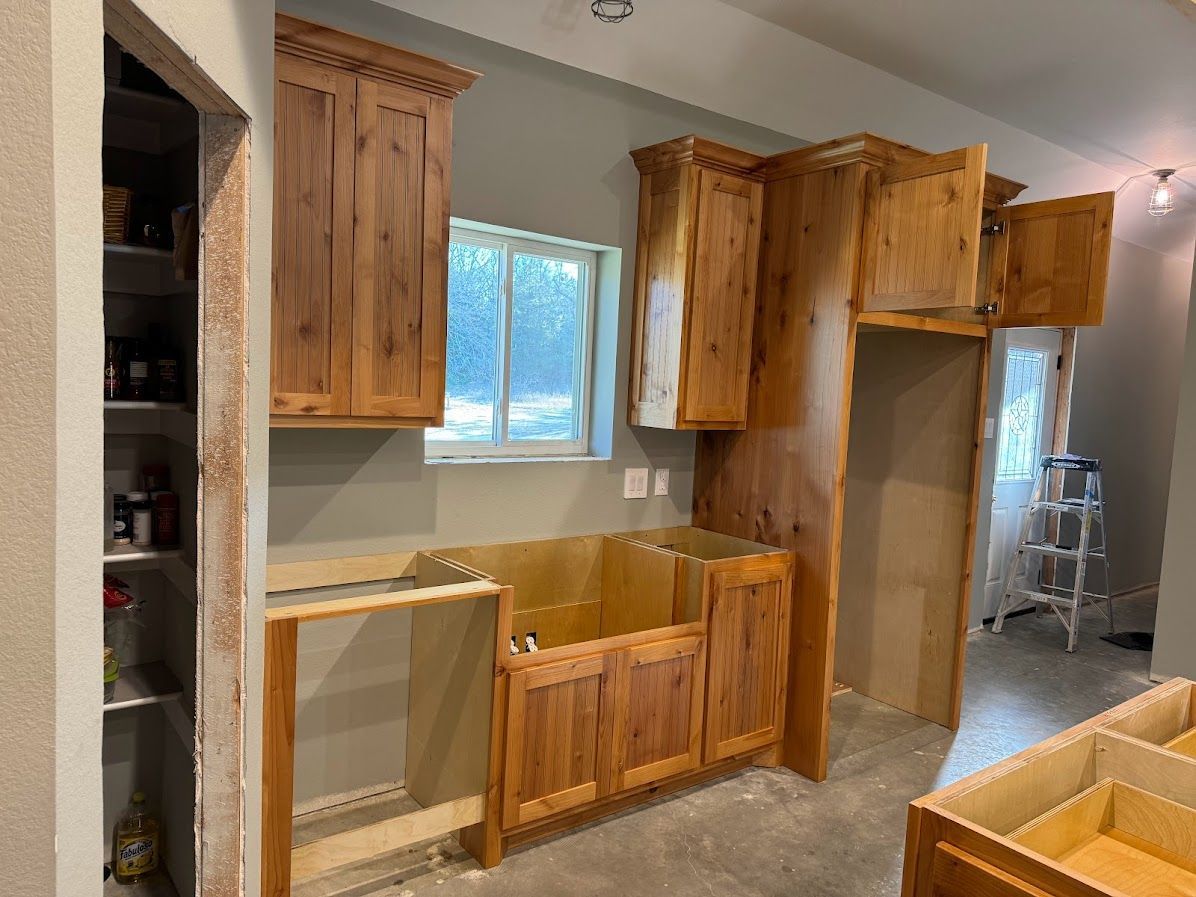 A kitchen under construction with wooden cabinets and a window.