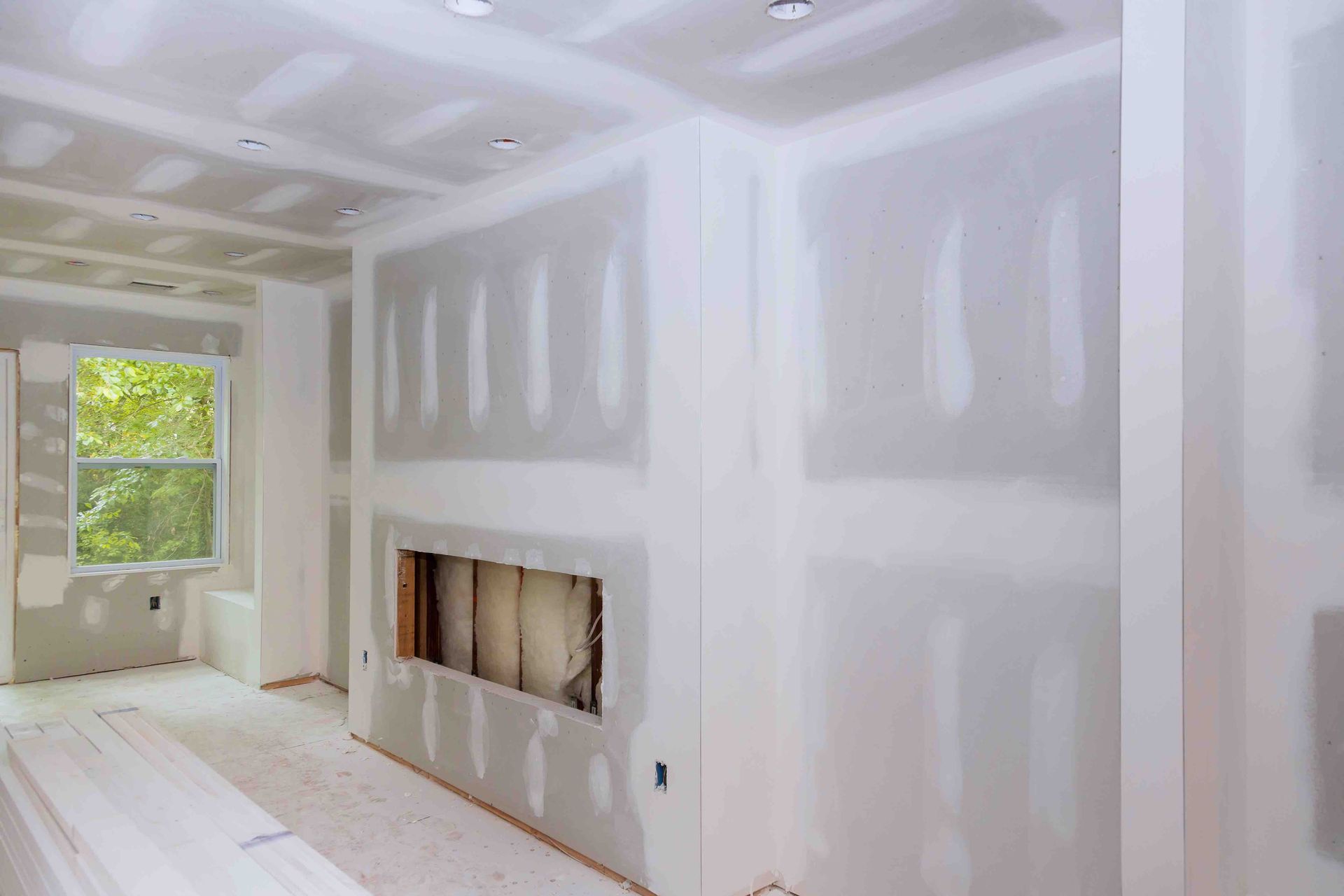 A room with drywall walls and a fireplace in it.
