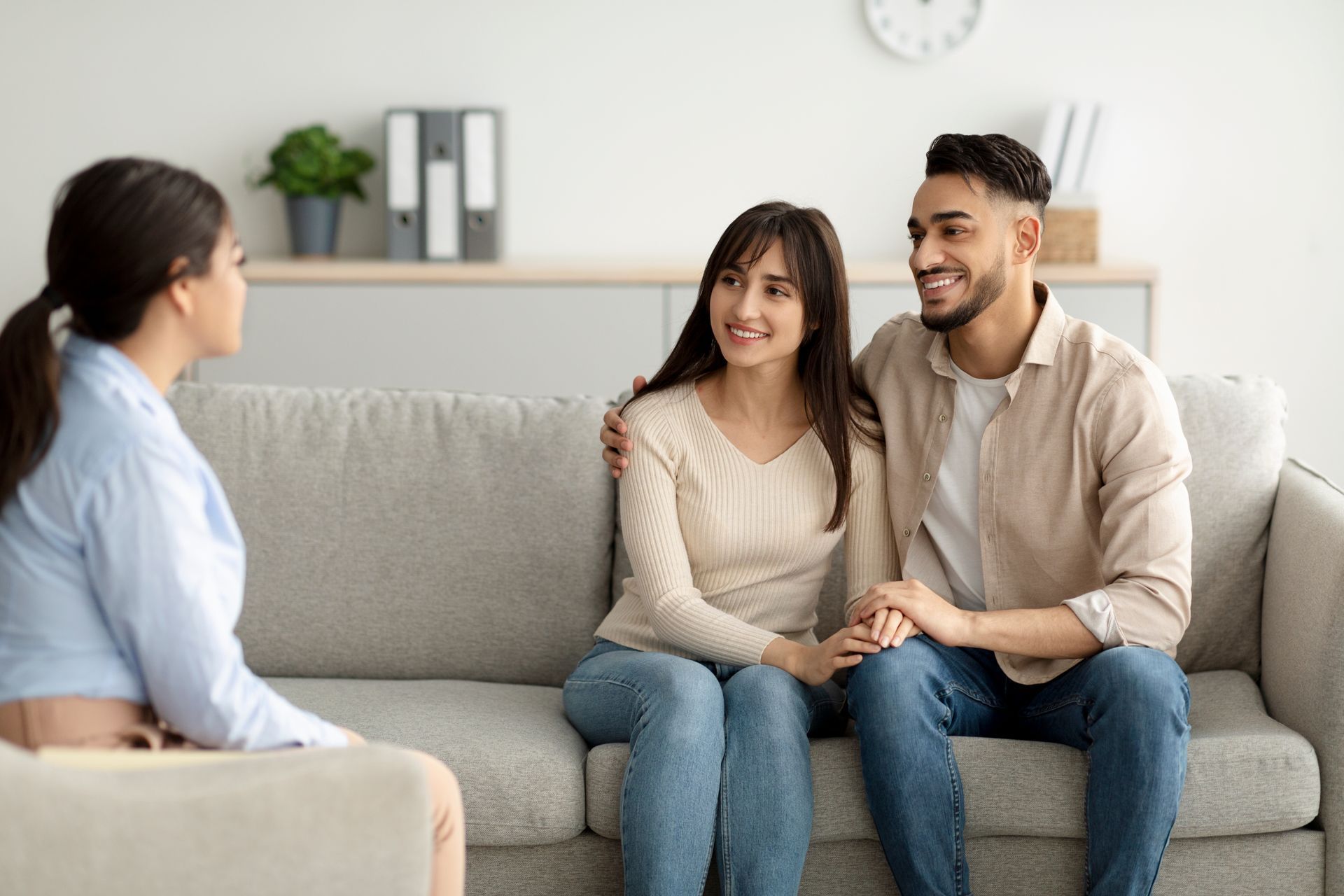 A young couple both smile while looking at their marriage counselor