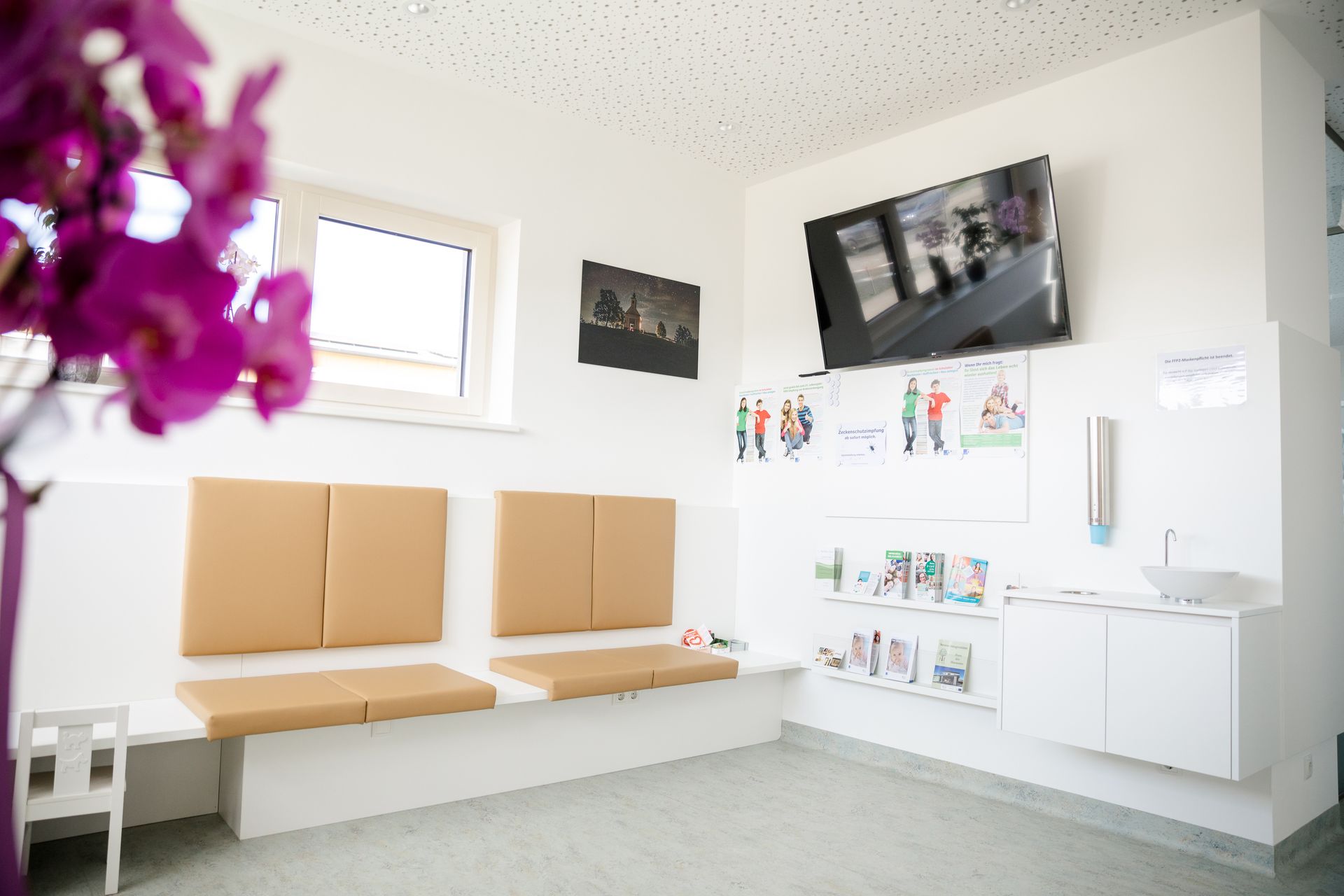 Ein Wartezimmer mit einer lila Blume im Vordergrund