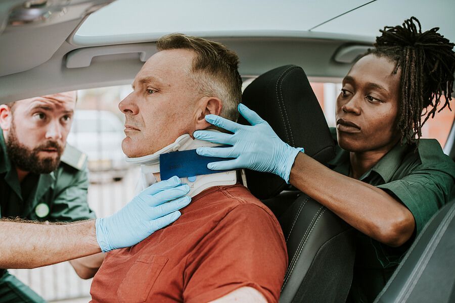 A man is sitting in a car with a neck brace on his neck.