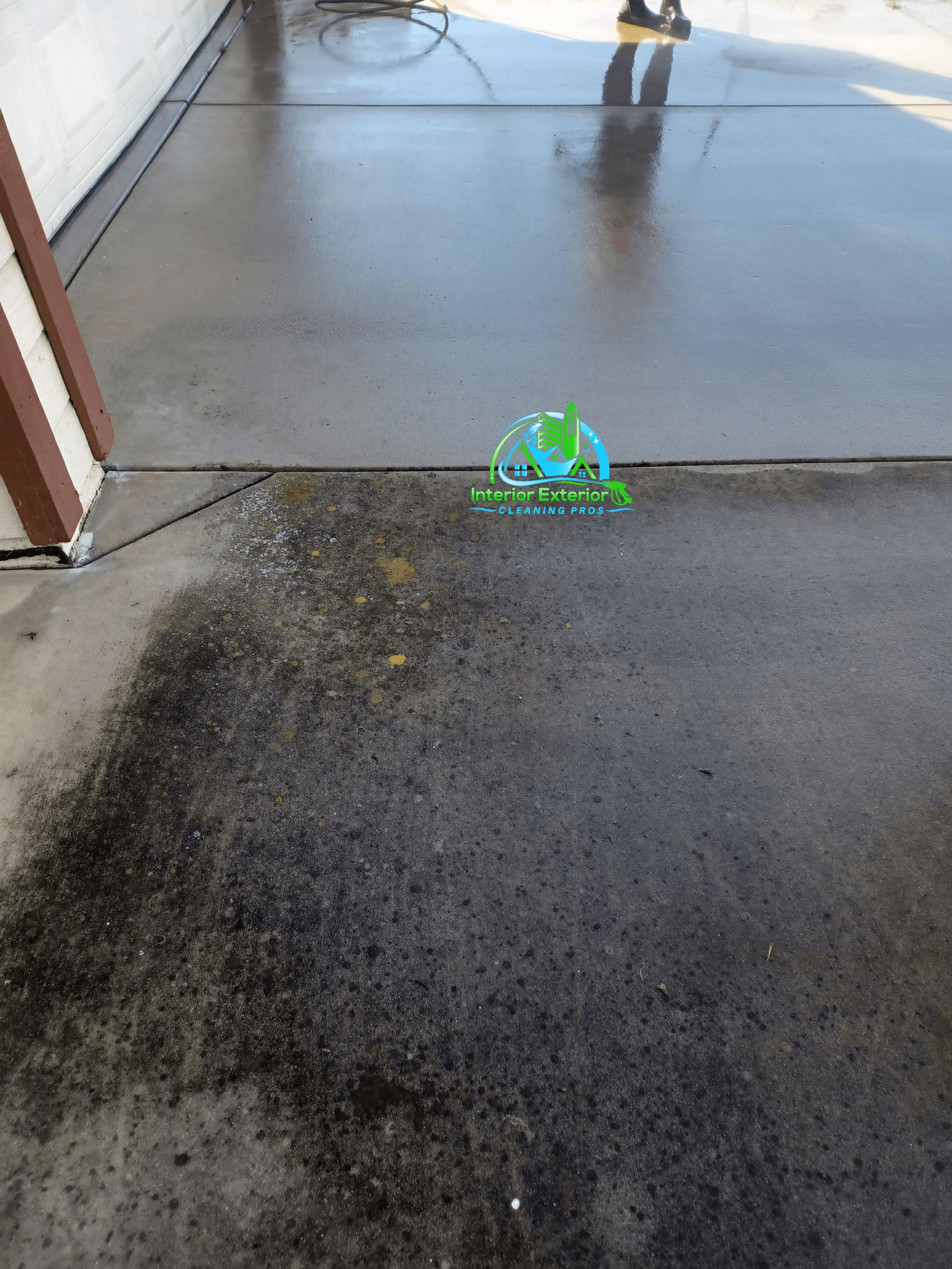 A person is cleaning a concrete driveway with a pressure washer.