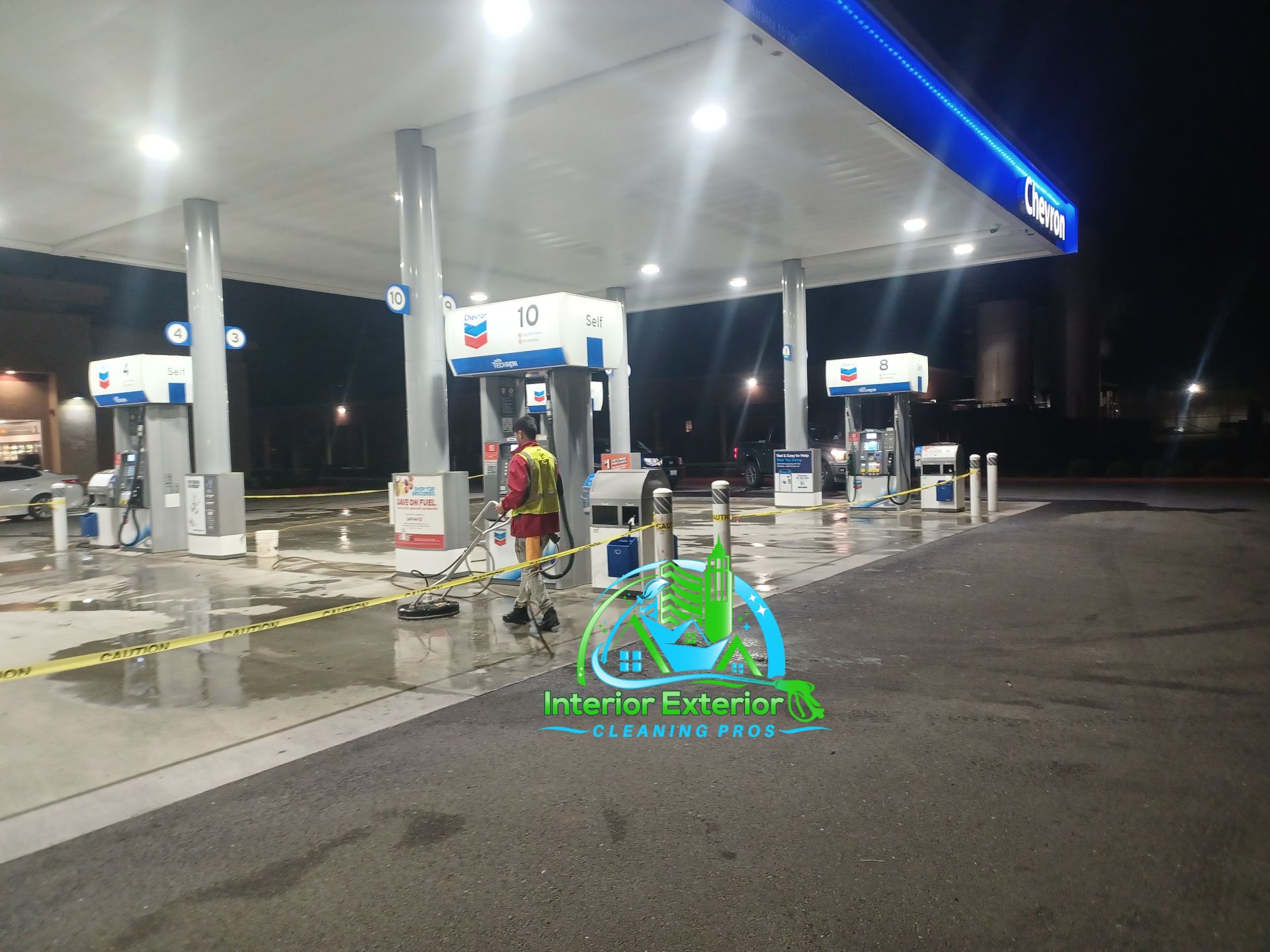 A man is cleaning a gas station at night