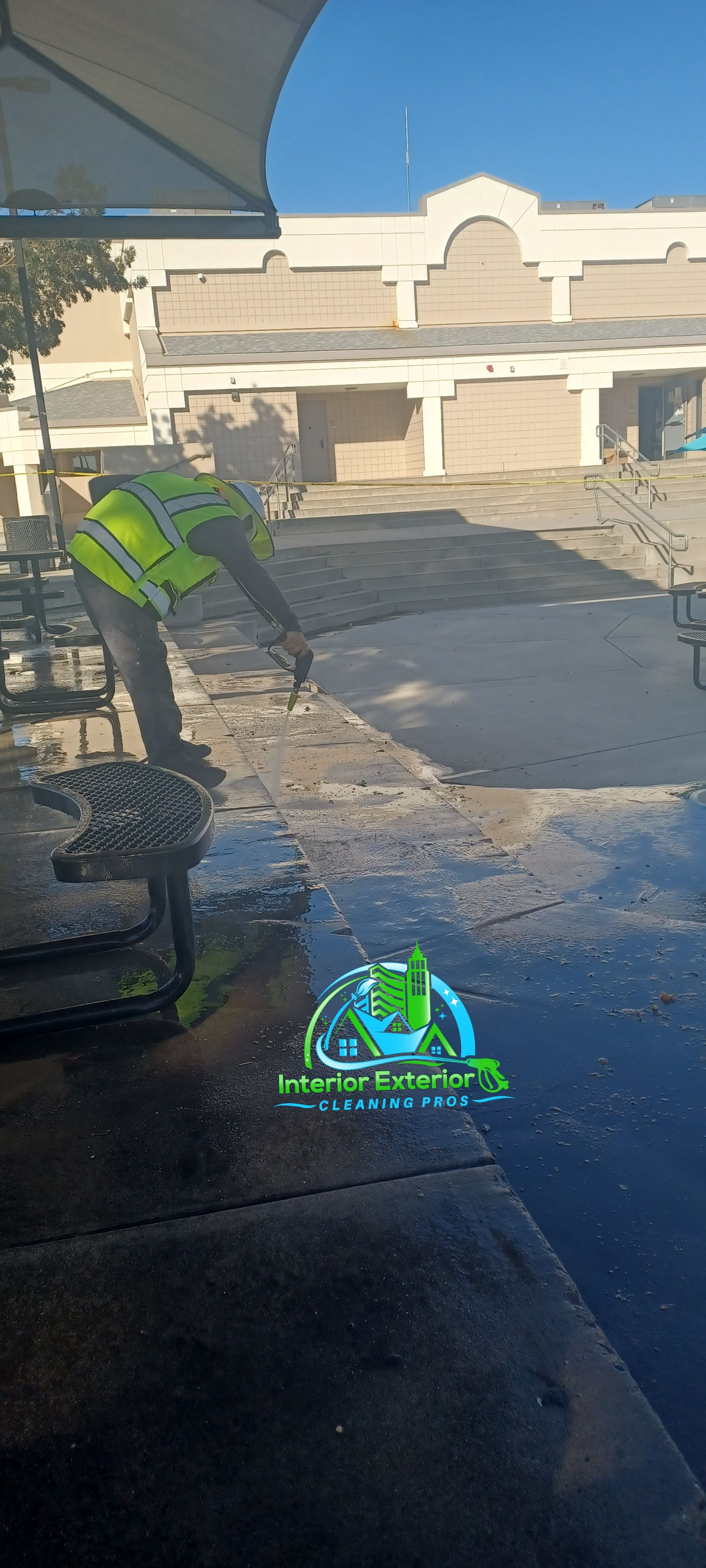 A person is cleaning a concrete driveway in front of a building.