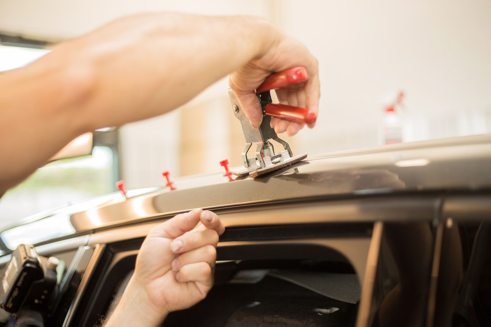 A person is fixing a car roof with a pair of pliers.