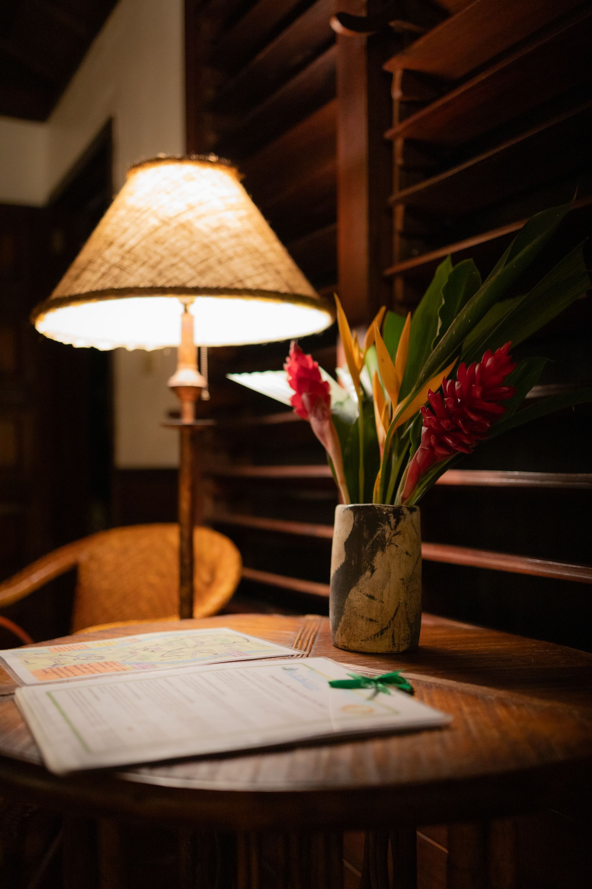 A vase of flowers sits on a table next to a lamp