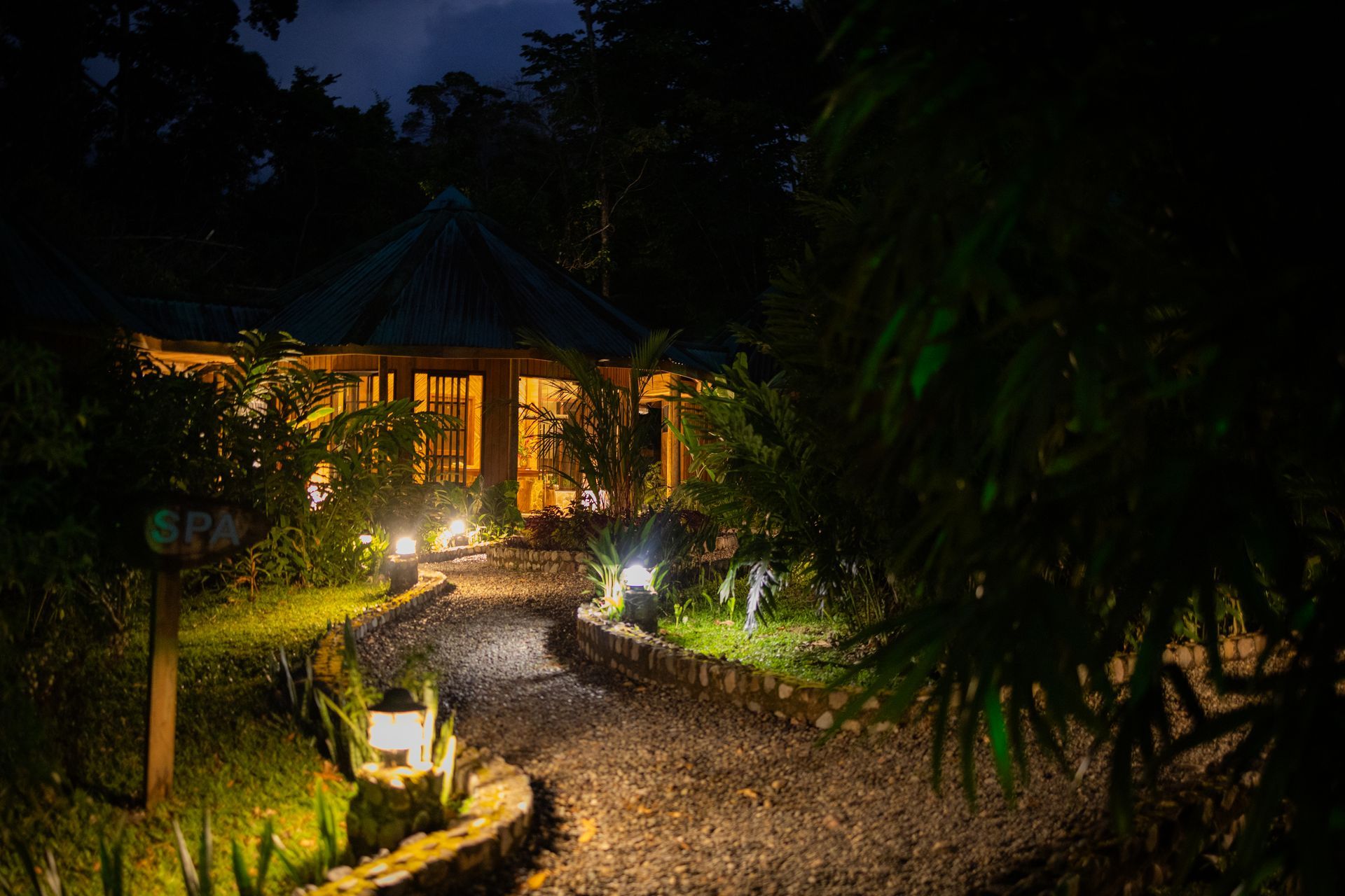 A path leading to a house in the woods at night.