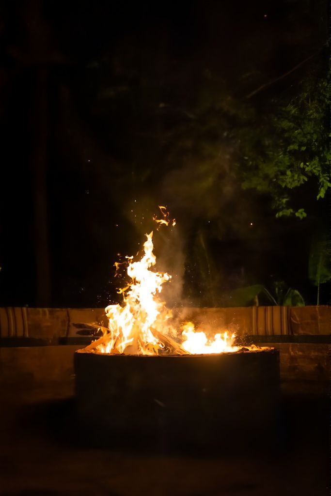 A fire pit is lit up at night in the woods.