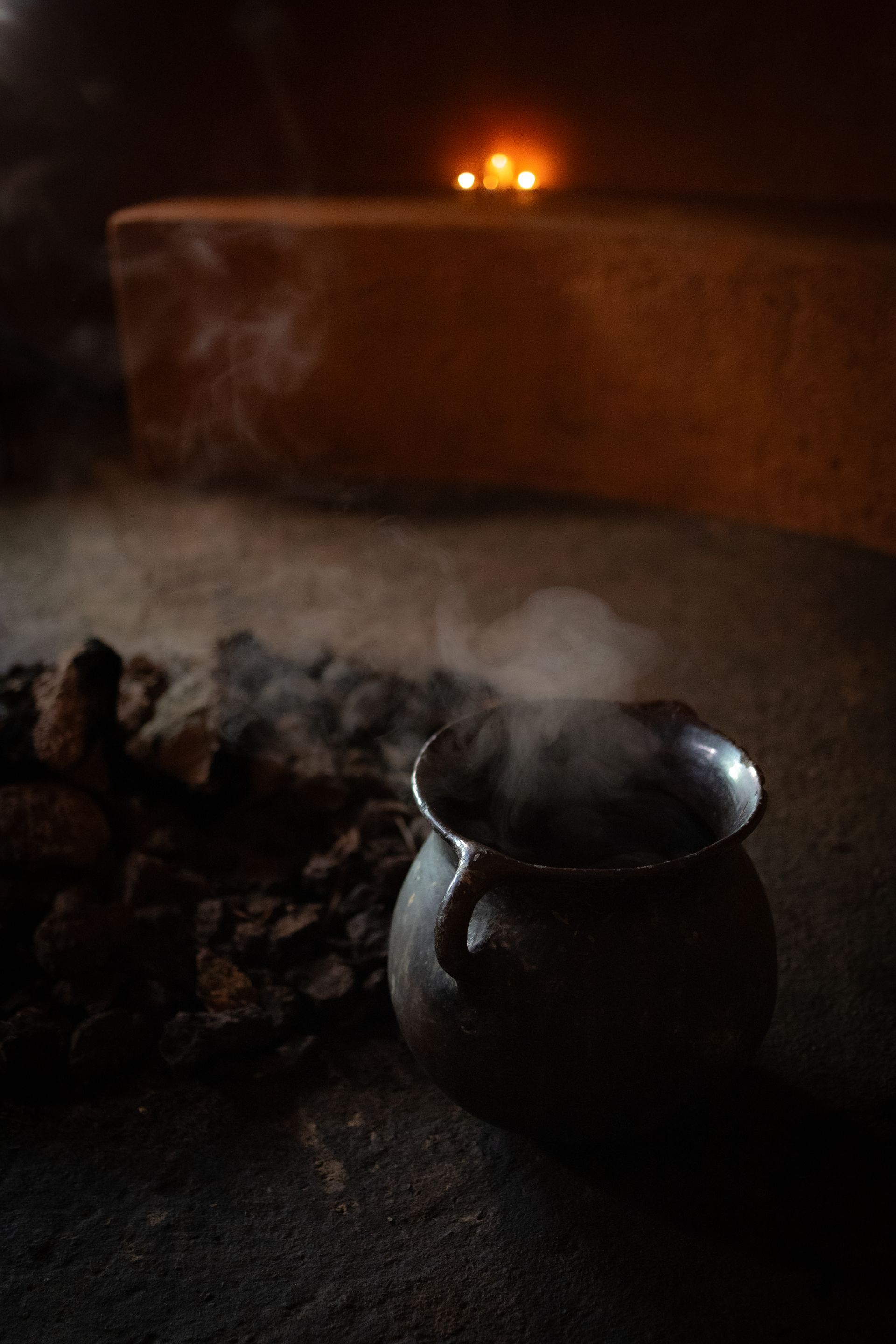 A pot of steam is coming out of it in a dark room.