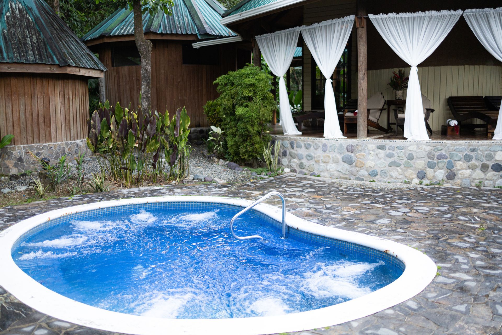 A large blue swimming pool is surrounded by a stone wall
