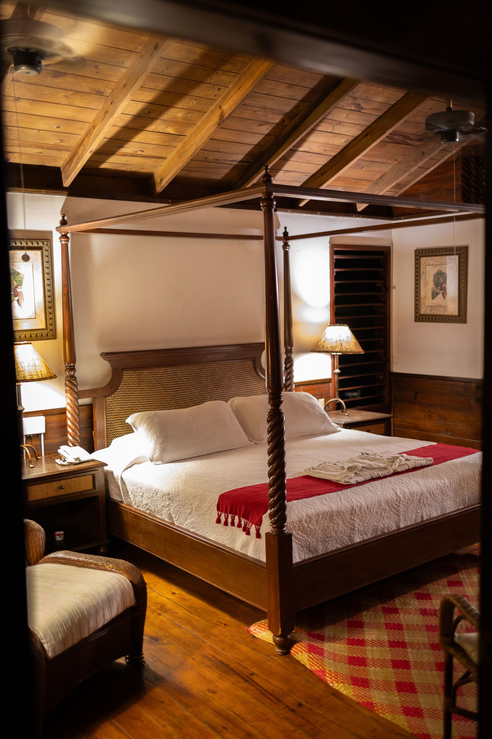 A bedroom with a four poster bed and a chair.
