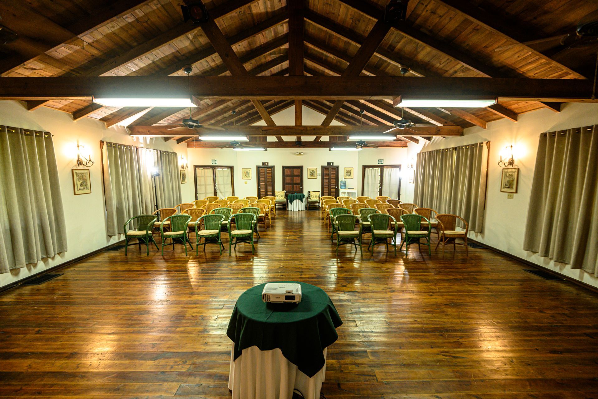 A large room with wooden floors and a table with a projector on it.