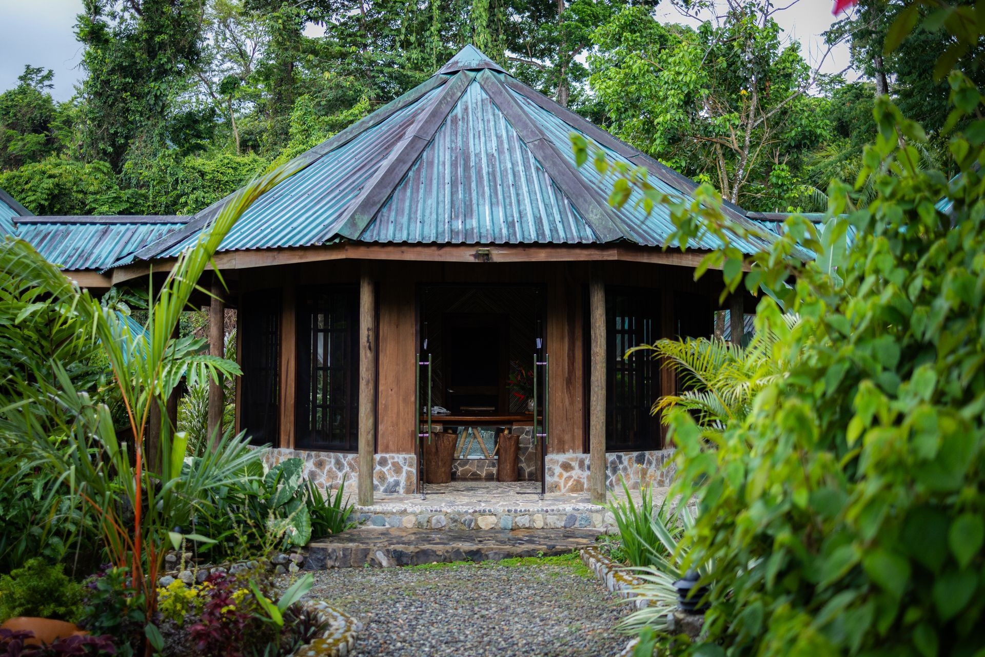 A small house with a blue roof is surrounded by trees and bushes.