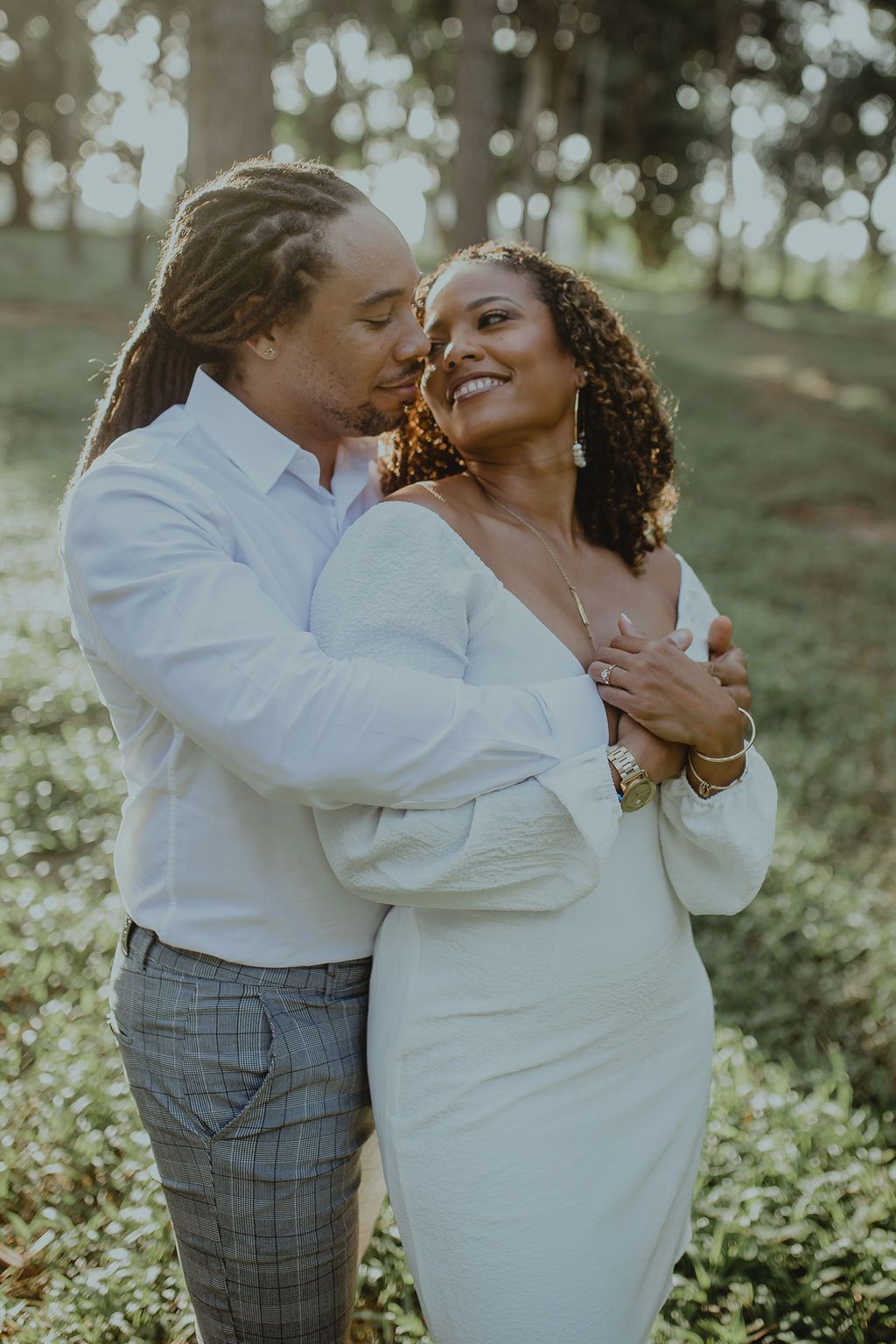 A man is kissing a woman on the cheek in a field.