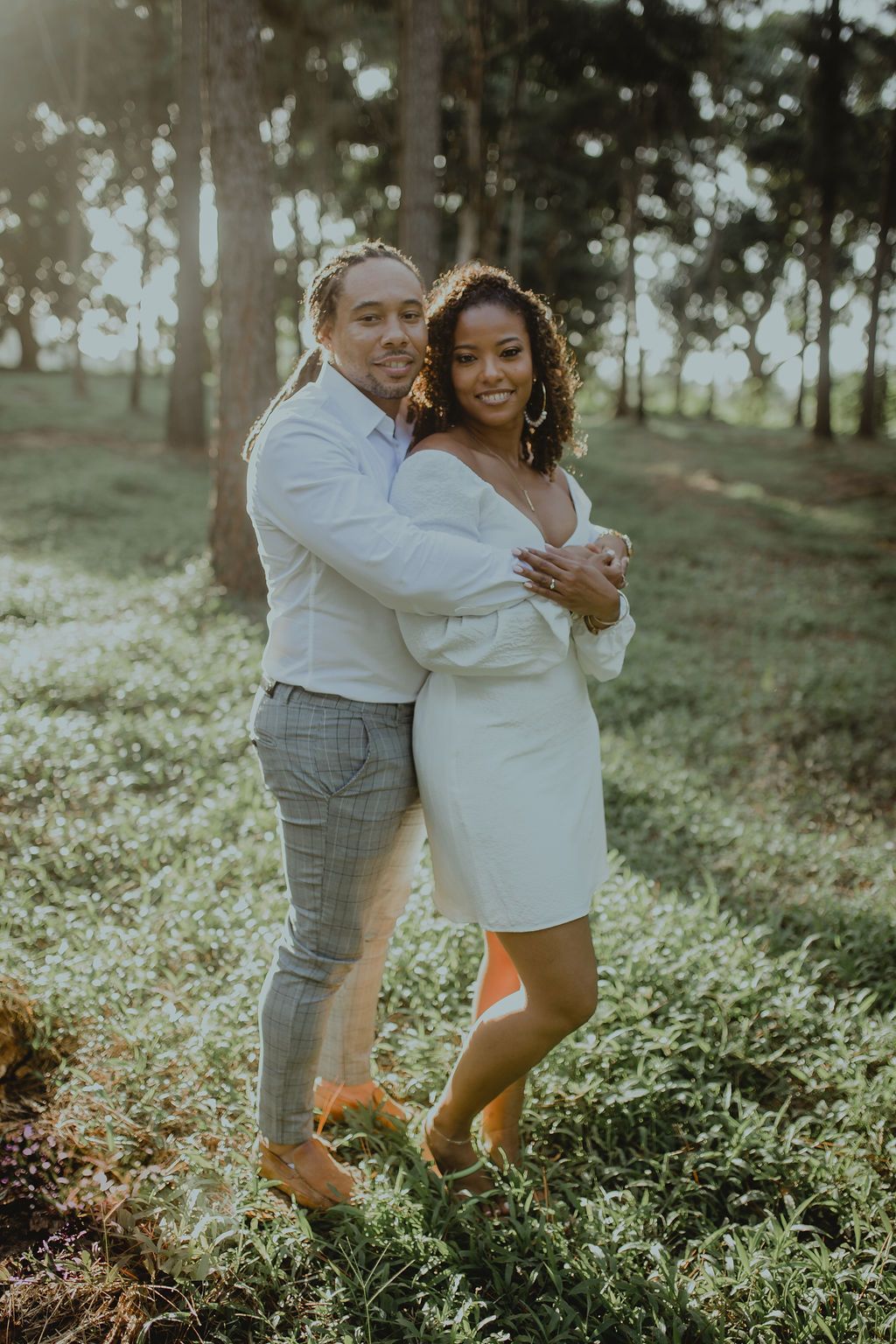 A man and a woman are posing for a picture in the woods.