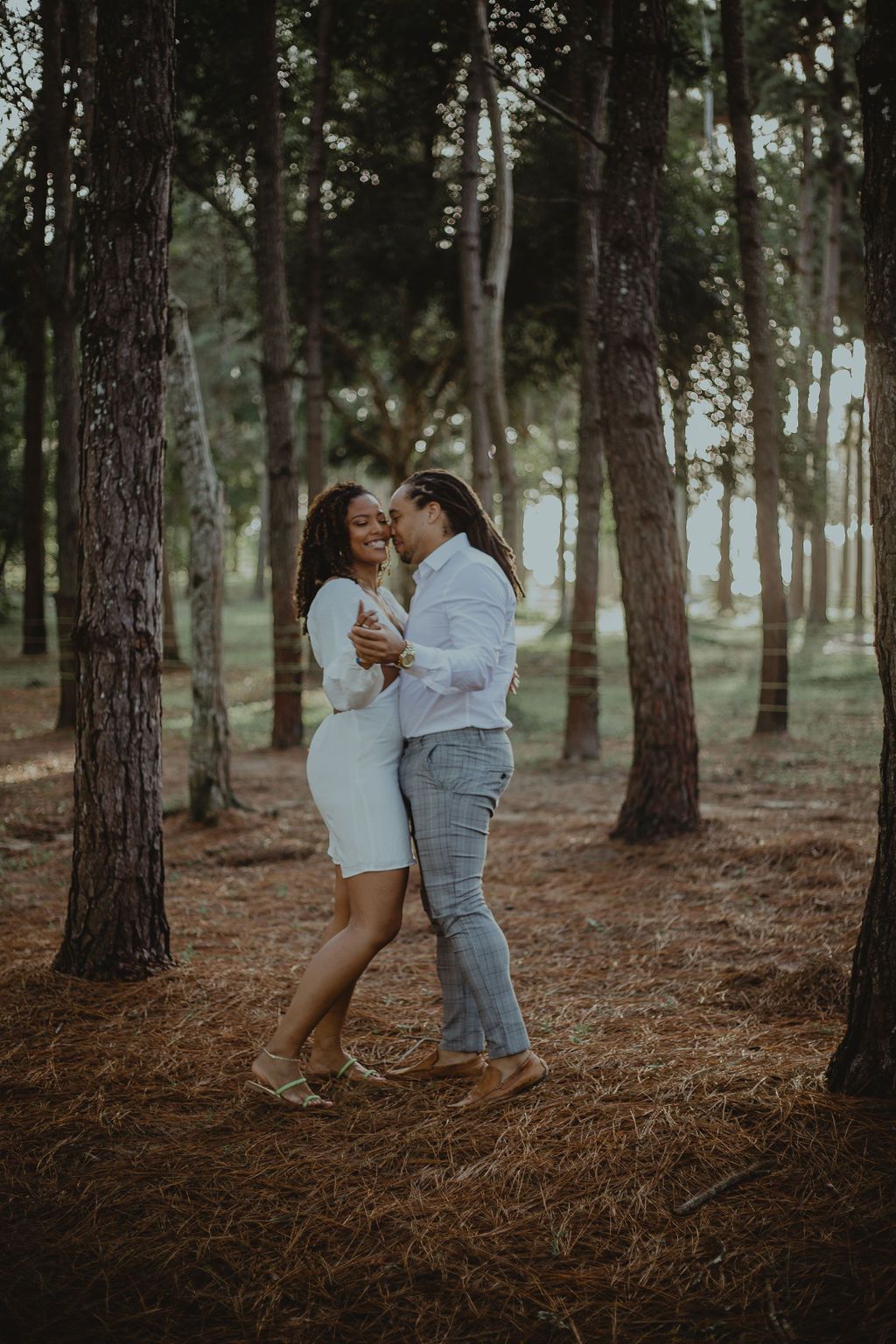 Two women are kissing in the middle of a forest.