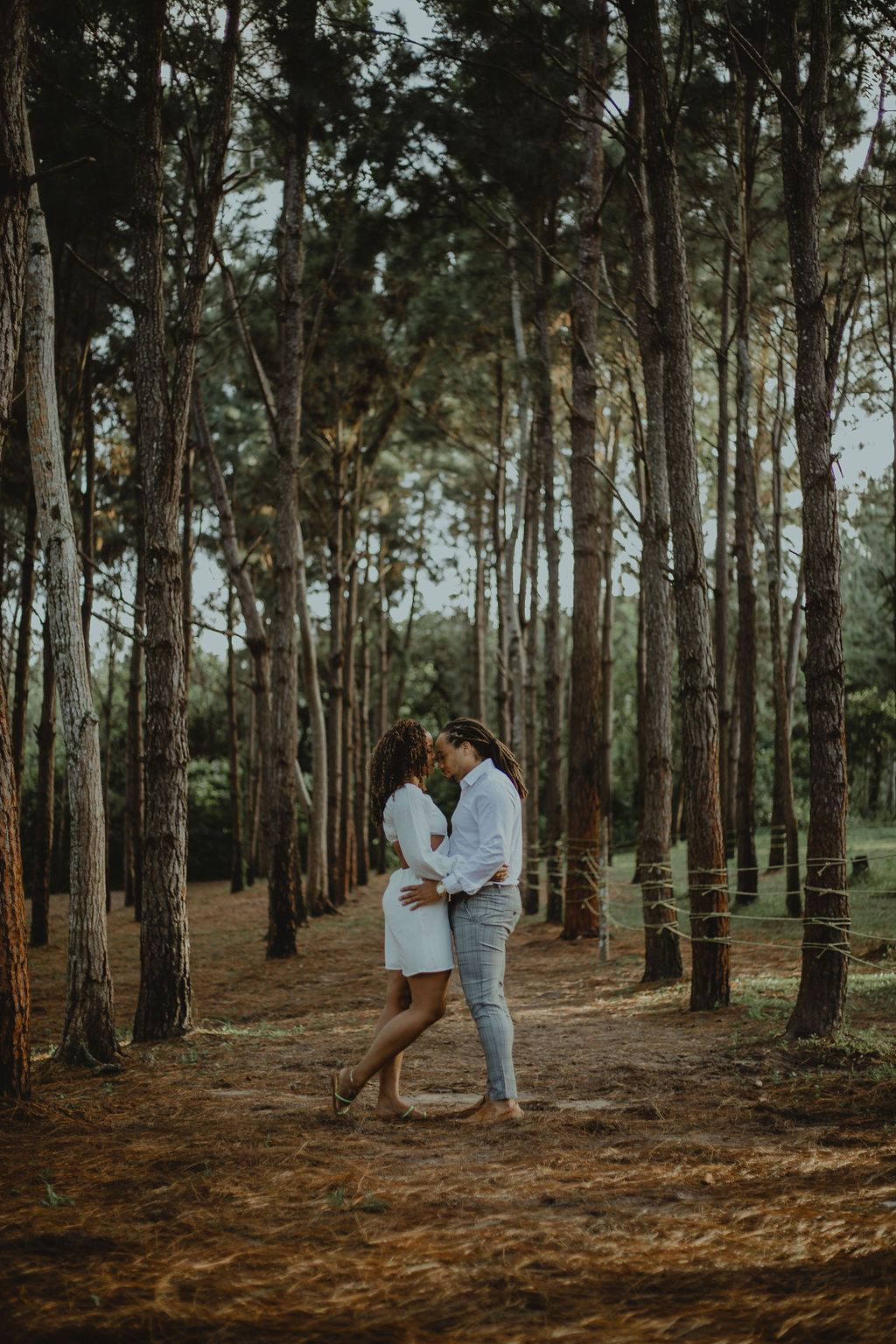 A man and a woman are kissing in the middle of a forest.