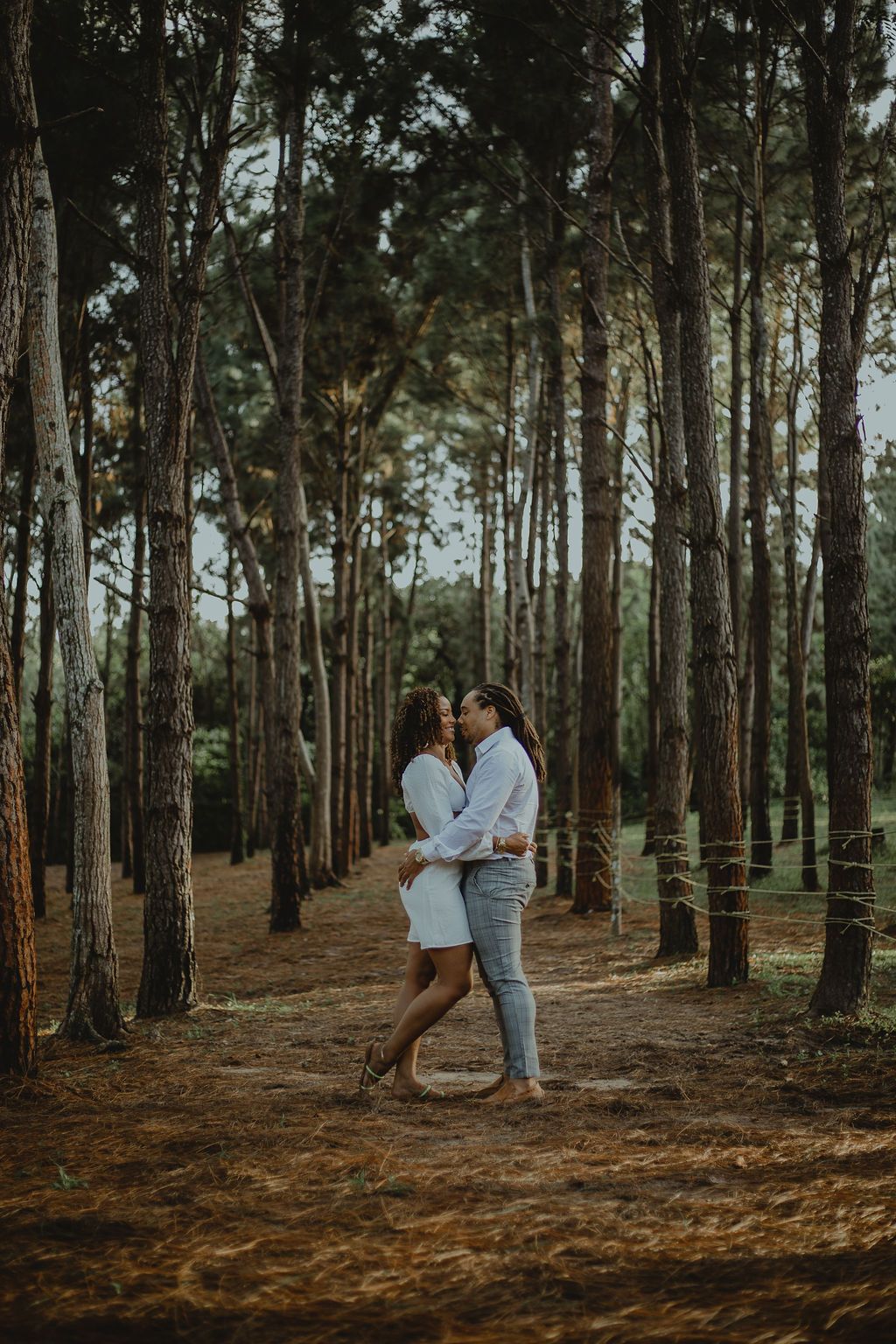 A couple is kissing in the middle of a forest.
