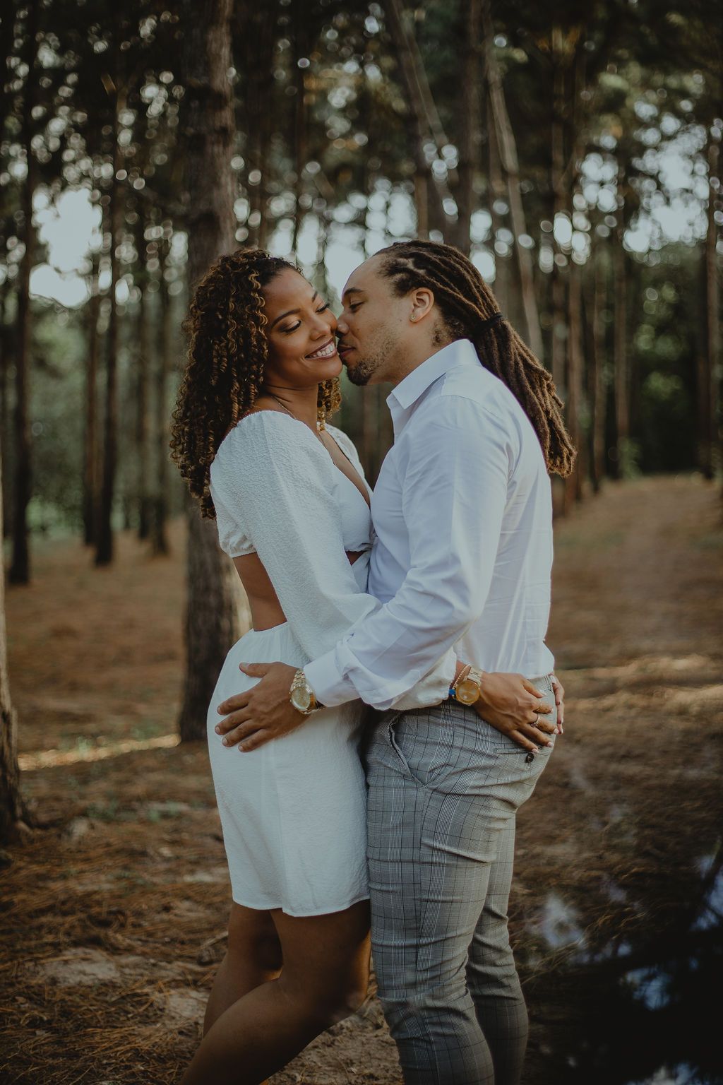 A man and a woman are kissing in the woods.