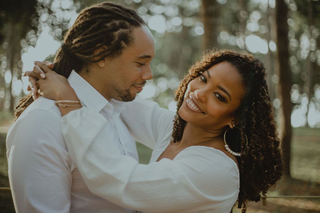A man and a woman are hugging each other in a park.