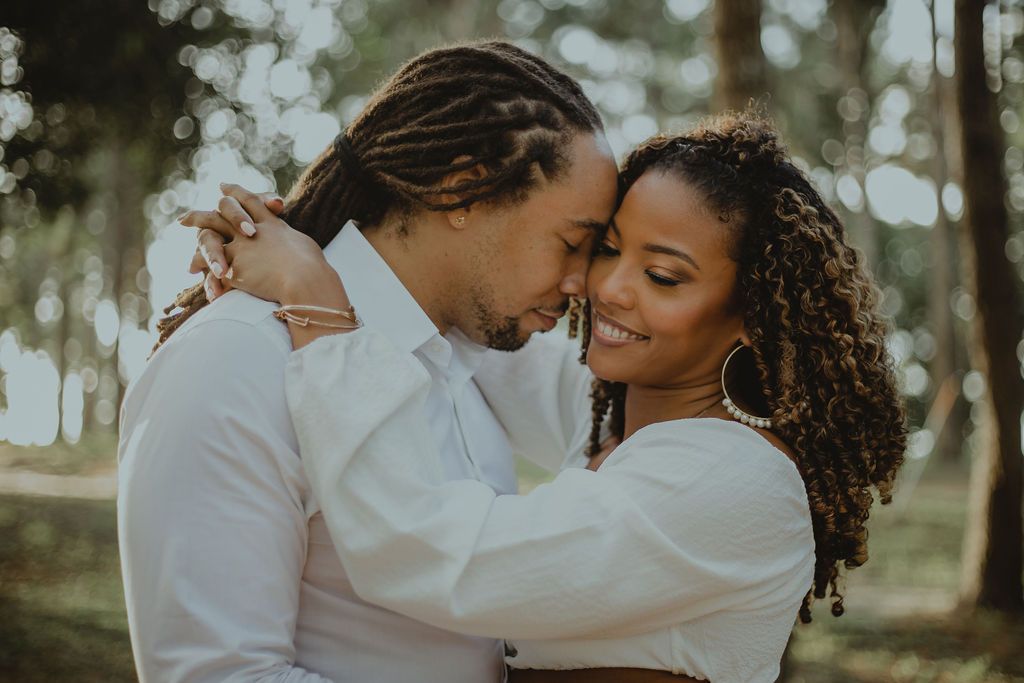 A man and a woman are hugging each other in a park.