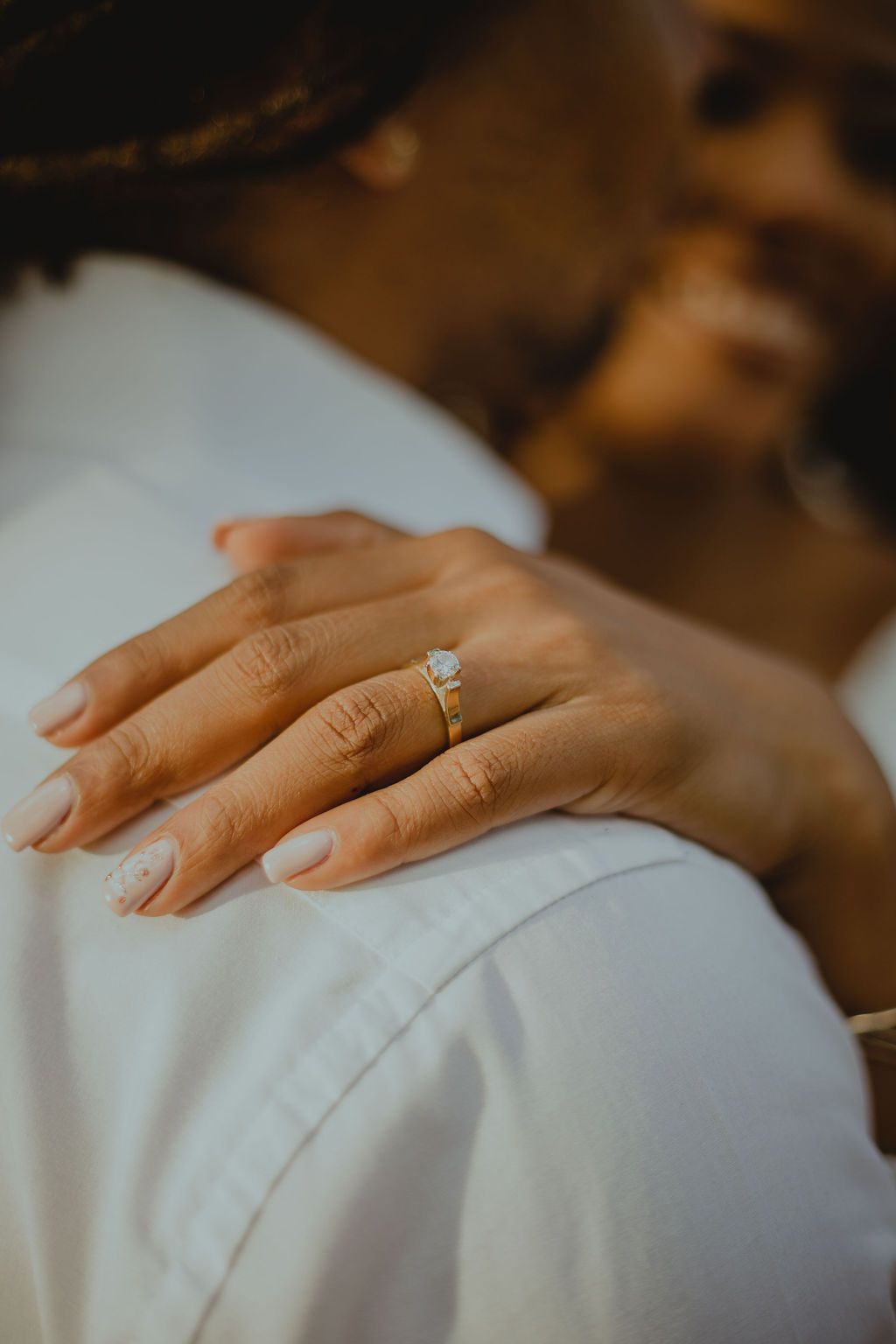 A close up of a woman 's hand with an engagement ring on it.