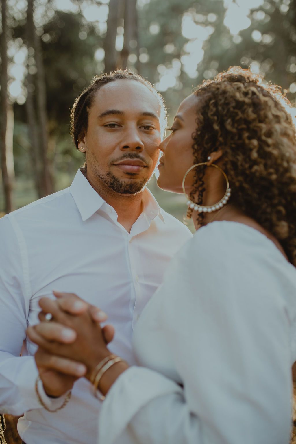 A woman is kissing a man on the cheek while holding hands.