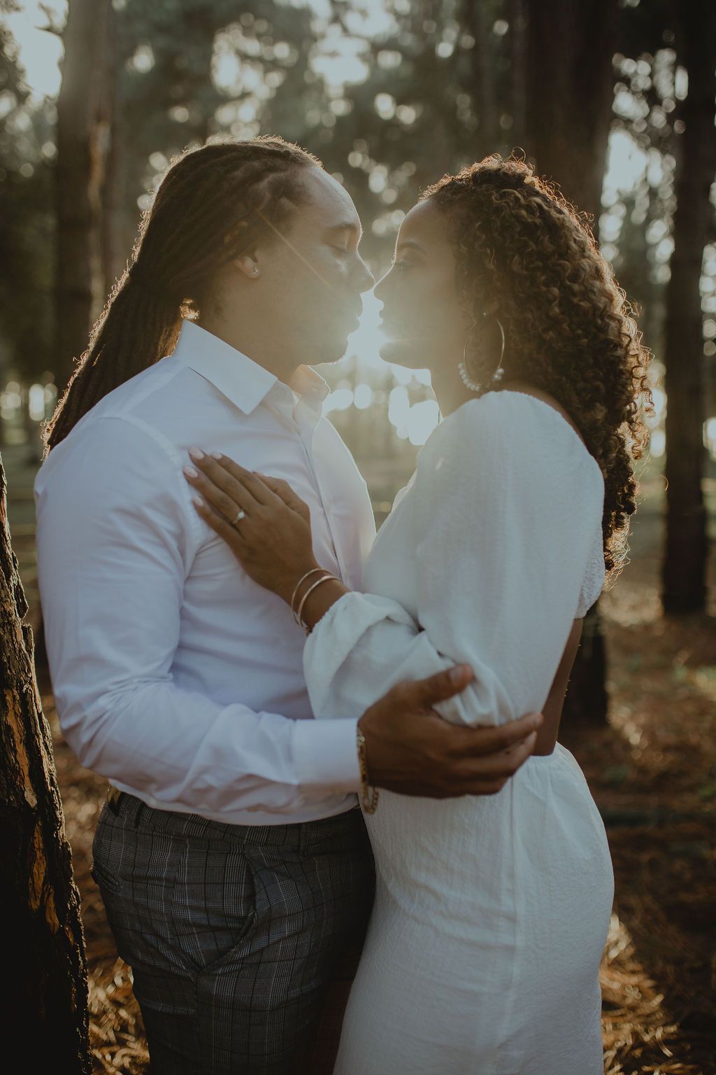 A man and a woman are kissing in the woods.