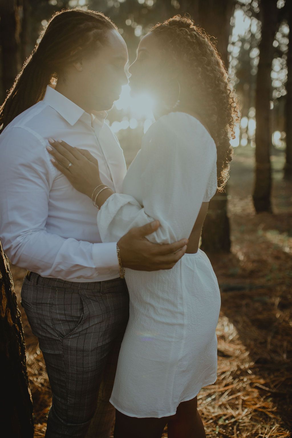 A man and a woman are kissing in the woods.