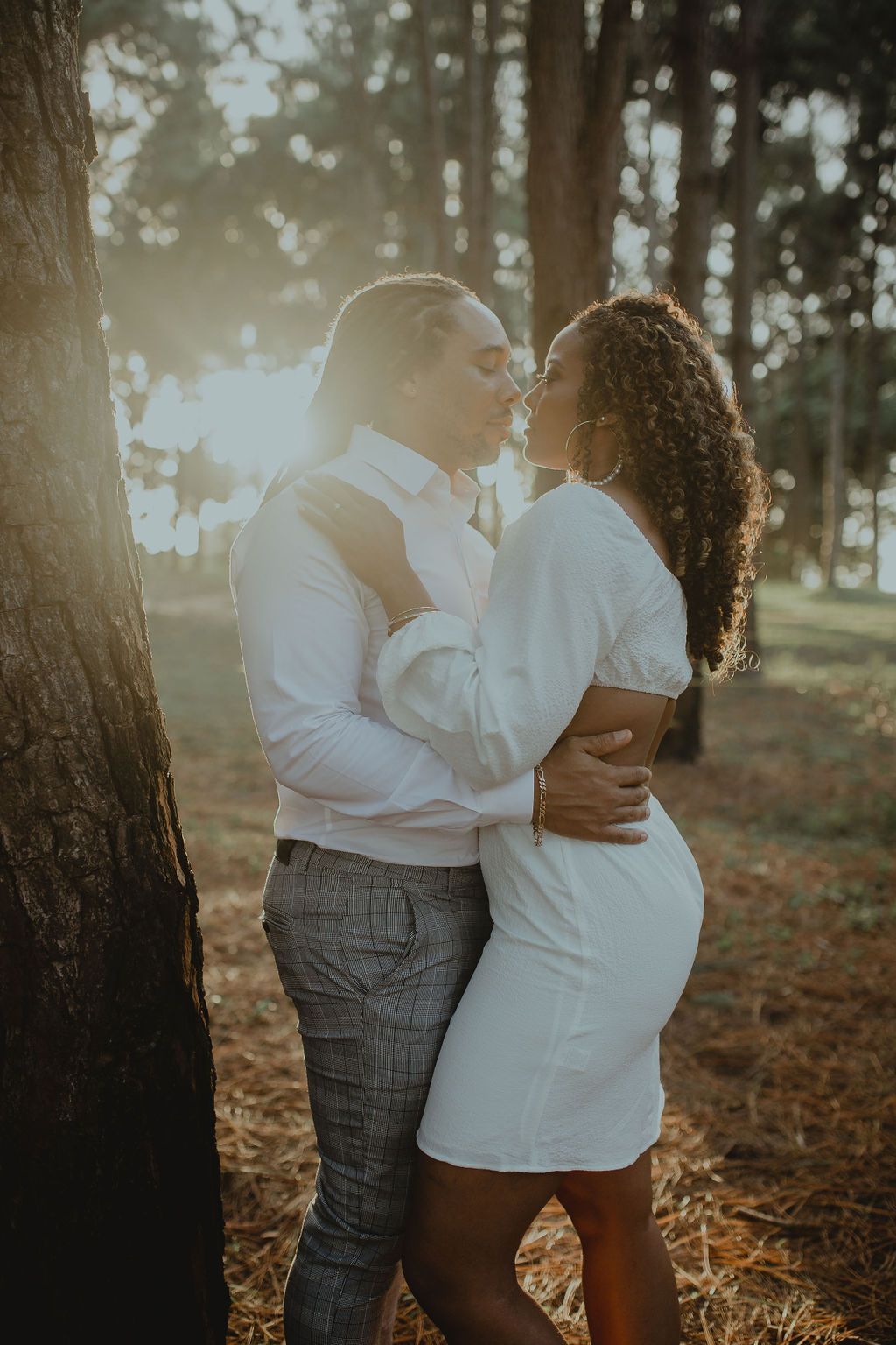 A man and a woman are kissing in the woods.