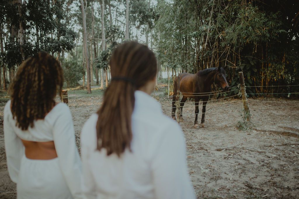 Two women are standing next to a horse in a field.