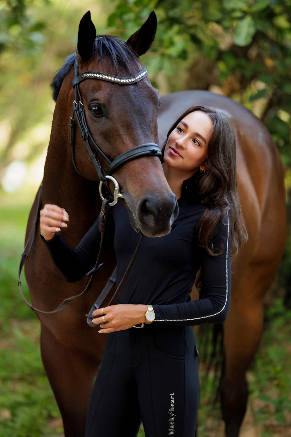 A woman is standing next to a brown horse.
