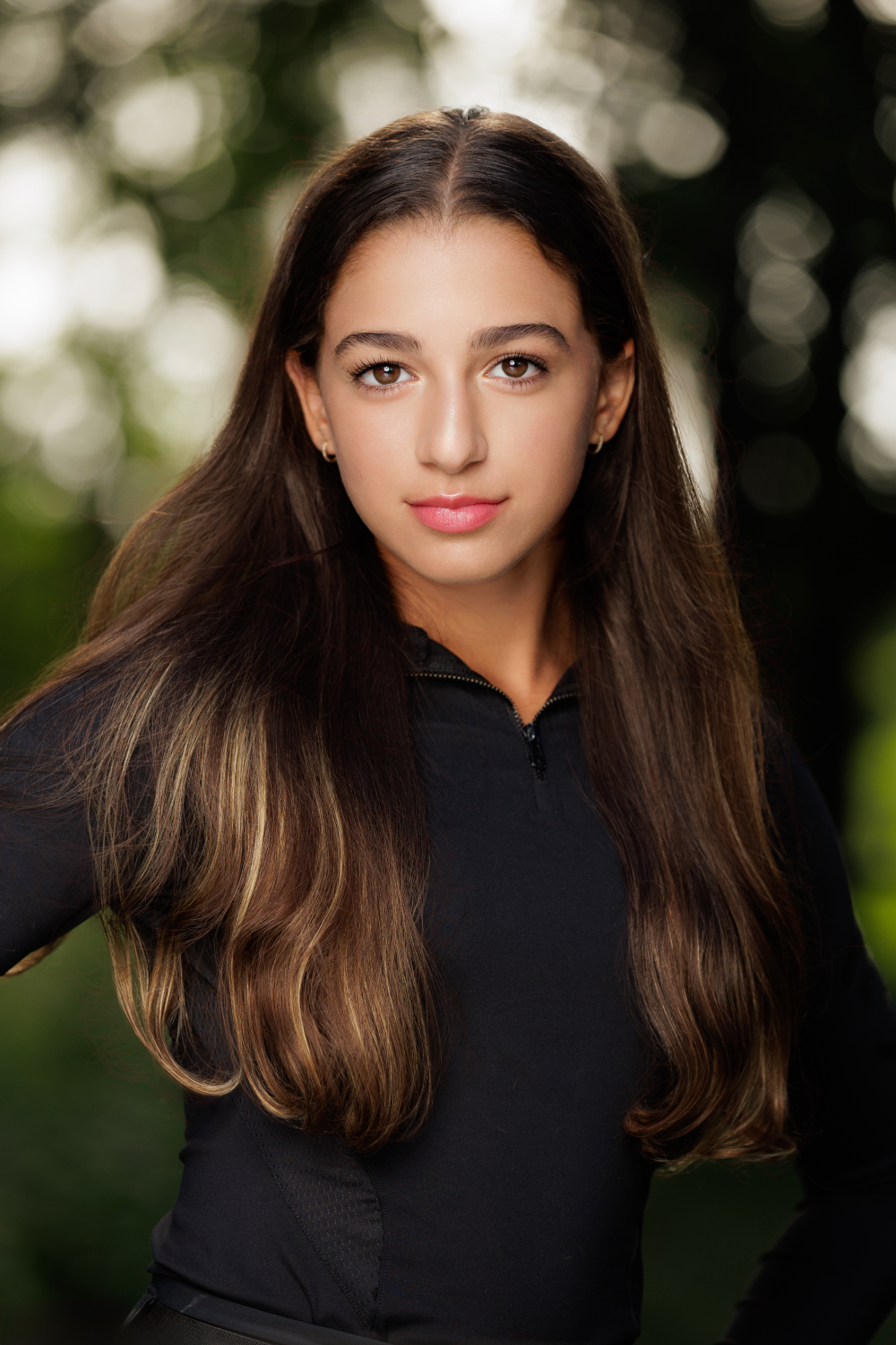 A young girl with long hair is wearing a black shirt and posing for a picture.