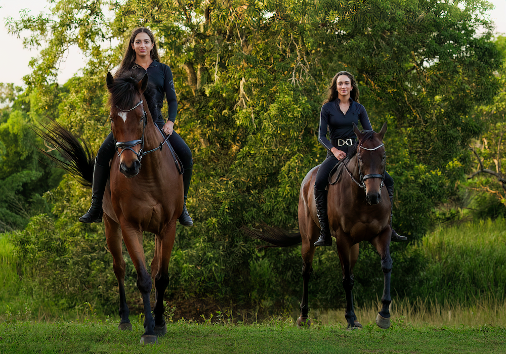 Two women are riding horses in a field.