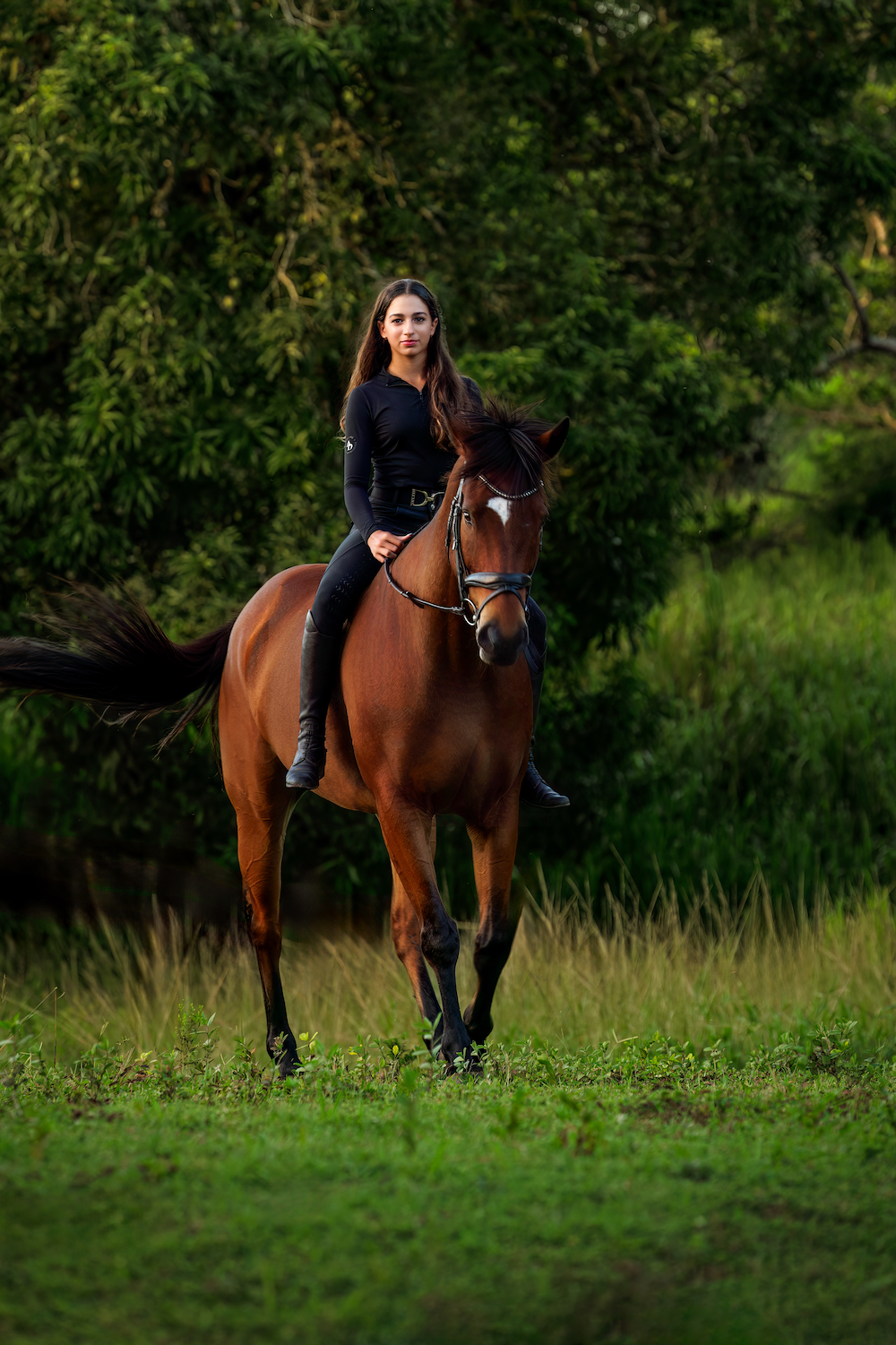 A woman is riding a brown horse in a field.