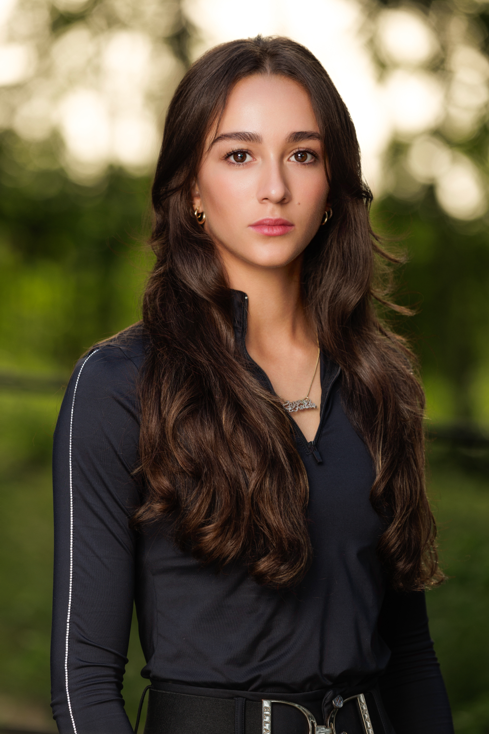 A woman with long hair is wearing a black shirt and a black belt.