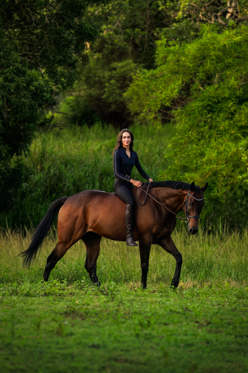 A woman is riding a brown horse in a field.