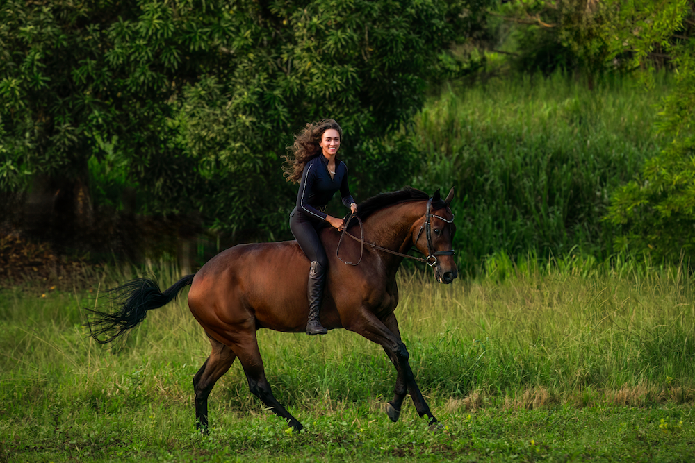 A woman is riding a brown horse in a field.