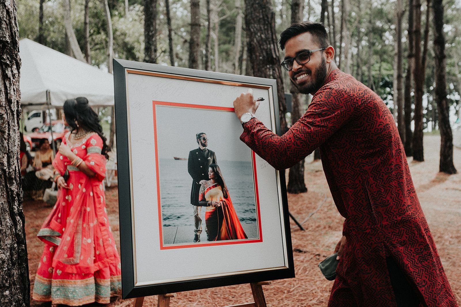 A man is holding a framed picture of a bride and groom.