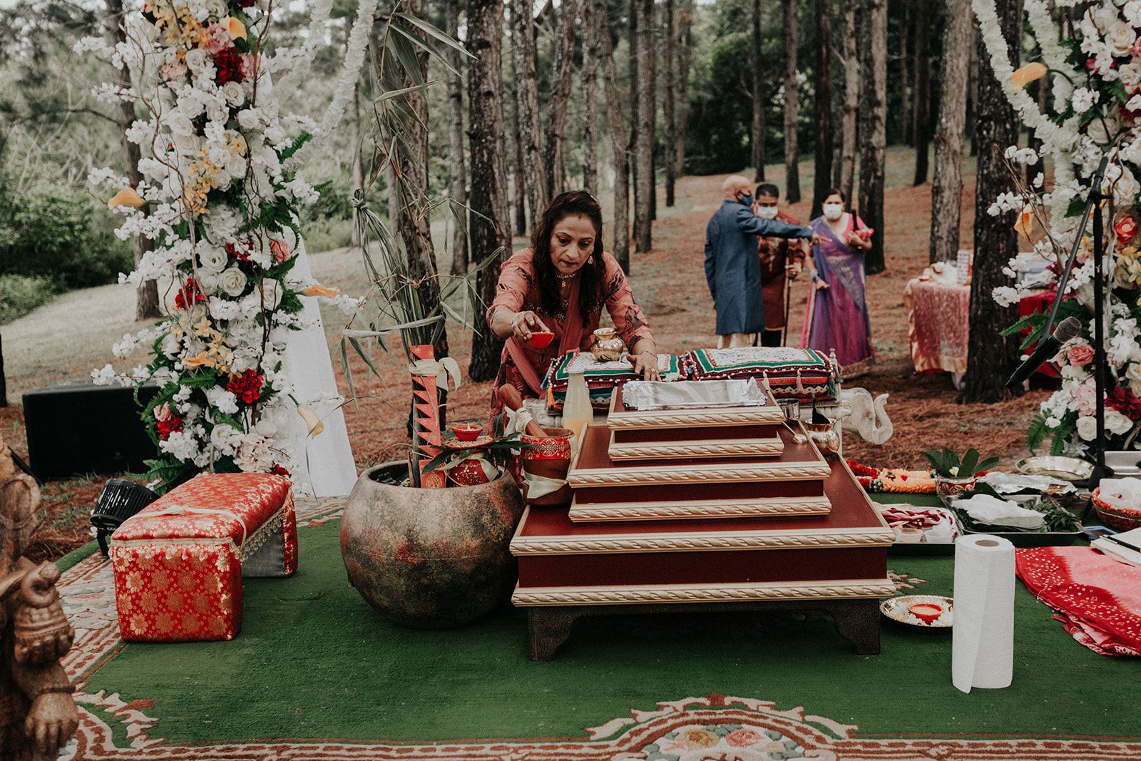 A woman is standing in front of a table in the woods.