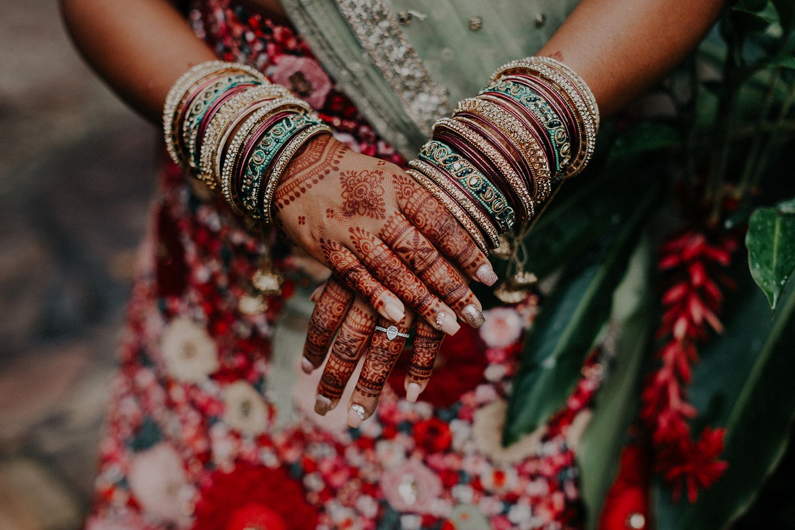 A close up of a woman 's hands with henna and bangles.